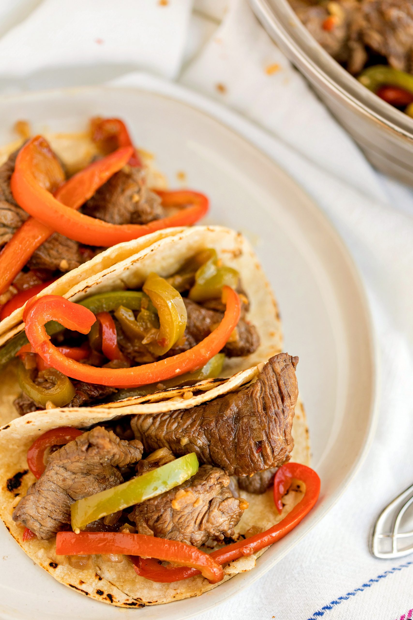 Beef with peppers and onions in wraps on a white plate 