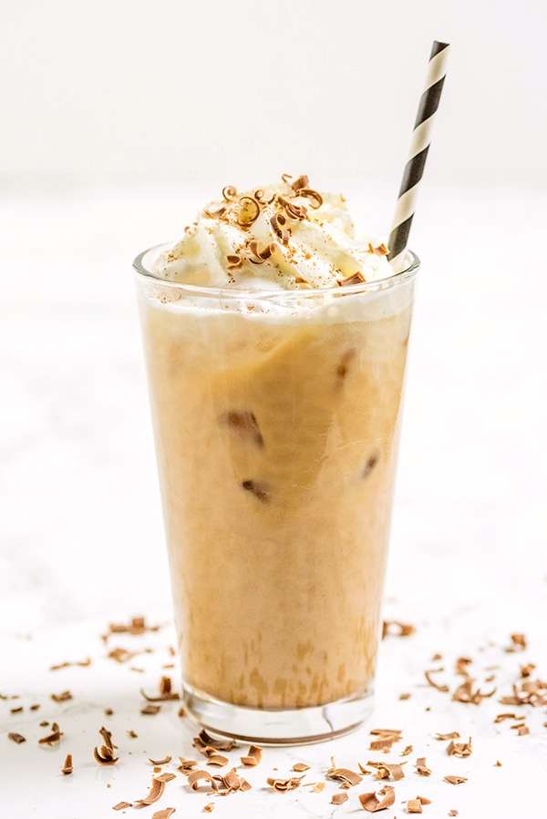 Glass with iced coffee, topped with whipped cream and cinnamon and shaved chocolate.