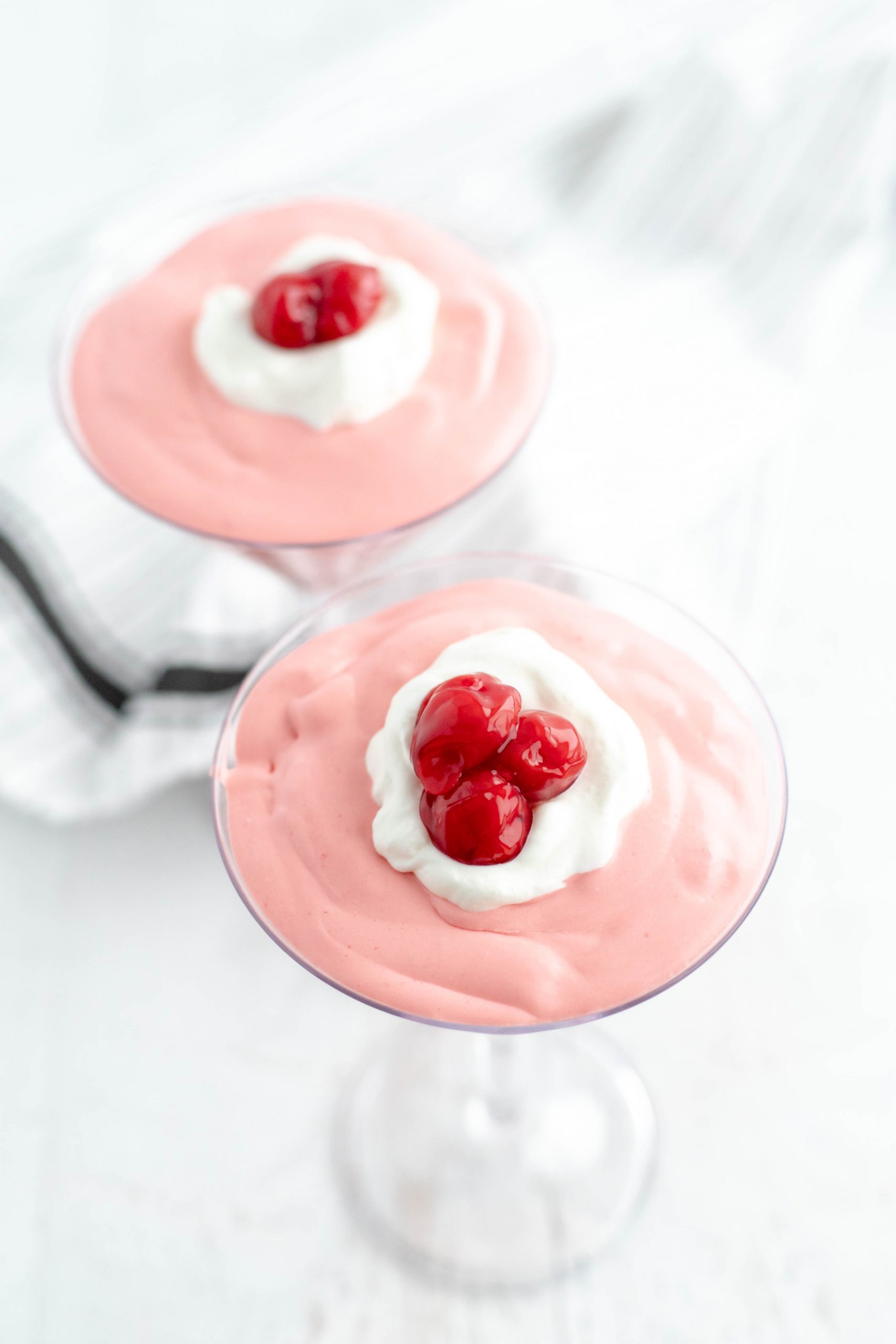Dessert cups with cherry mousse topped with whipped cream and cherries