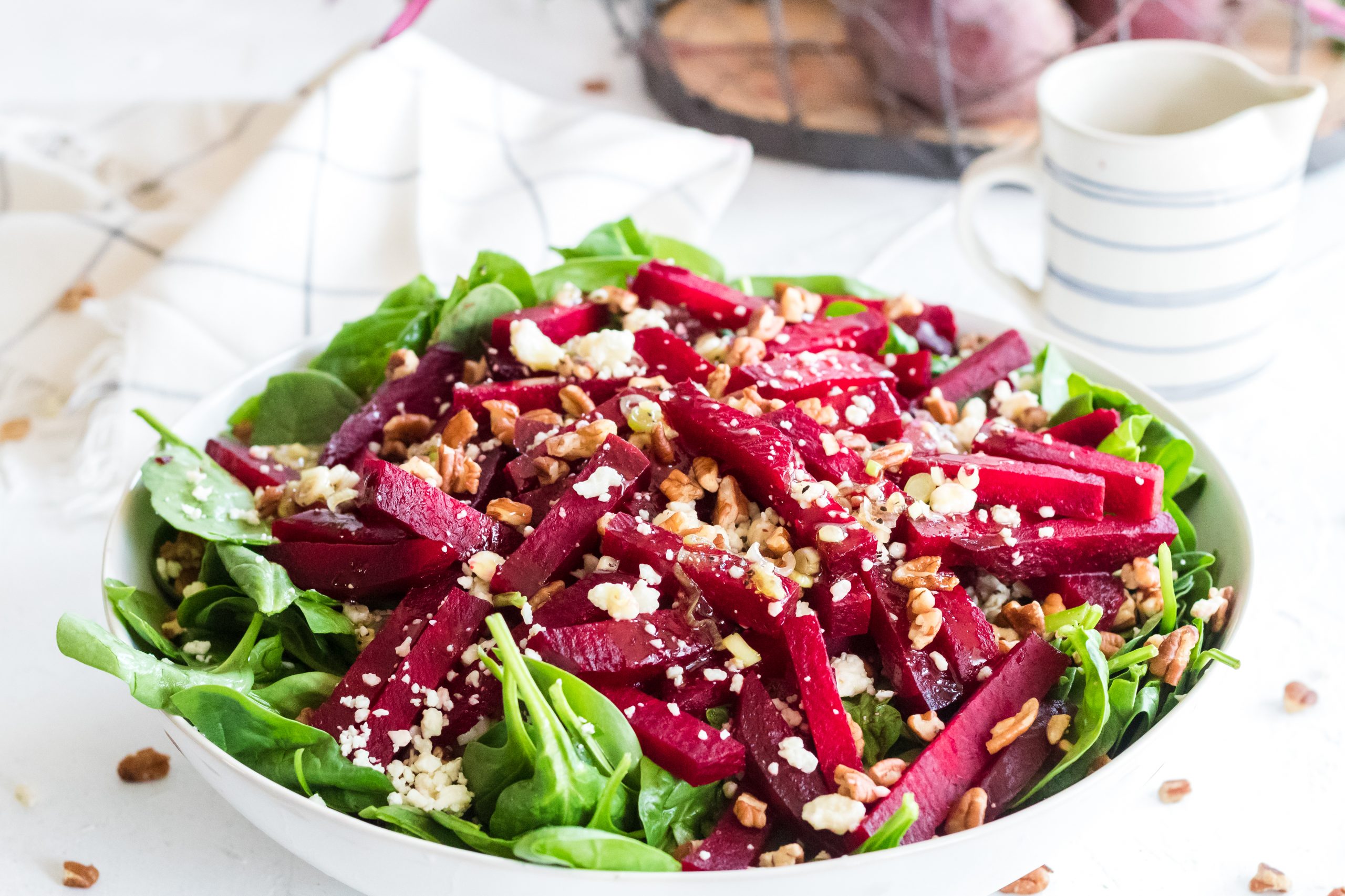 Fresh beets with crumbled blue cheese and pecans on a bed of greens in your favorite bowl