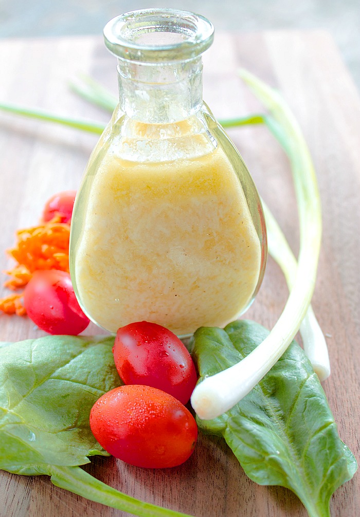 A carafe of homemade parmesan vinaigrette with fresh vegetables on table 