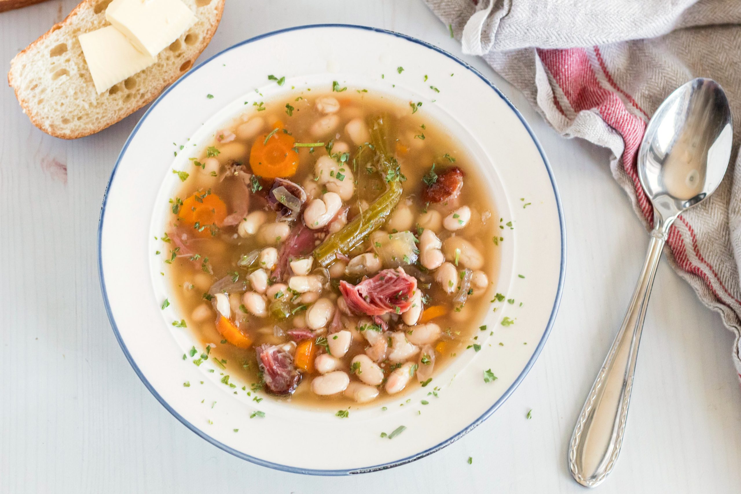 White bowl with ham and bean soup with carrots, ham, beans and a rich delicious broth