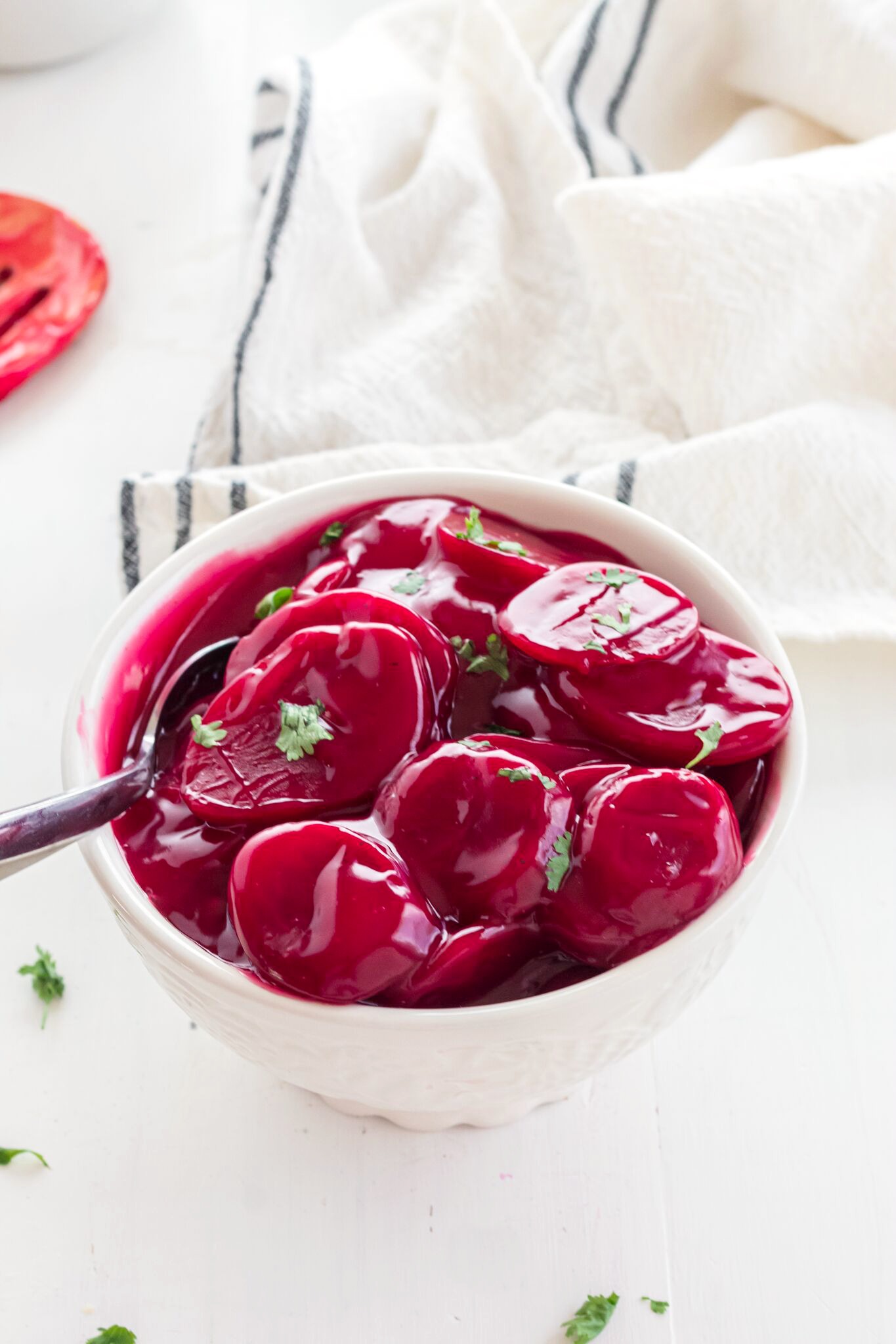A white bowl of of harvard beets garnished with fresh parsley