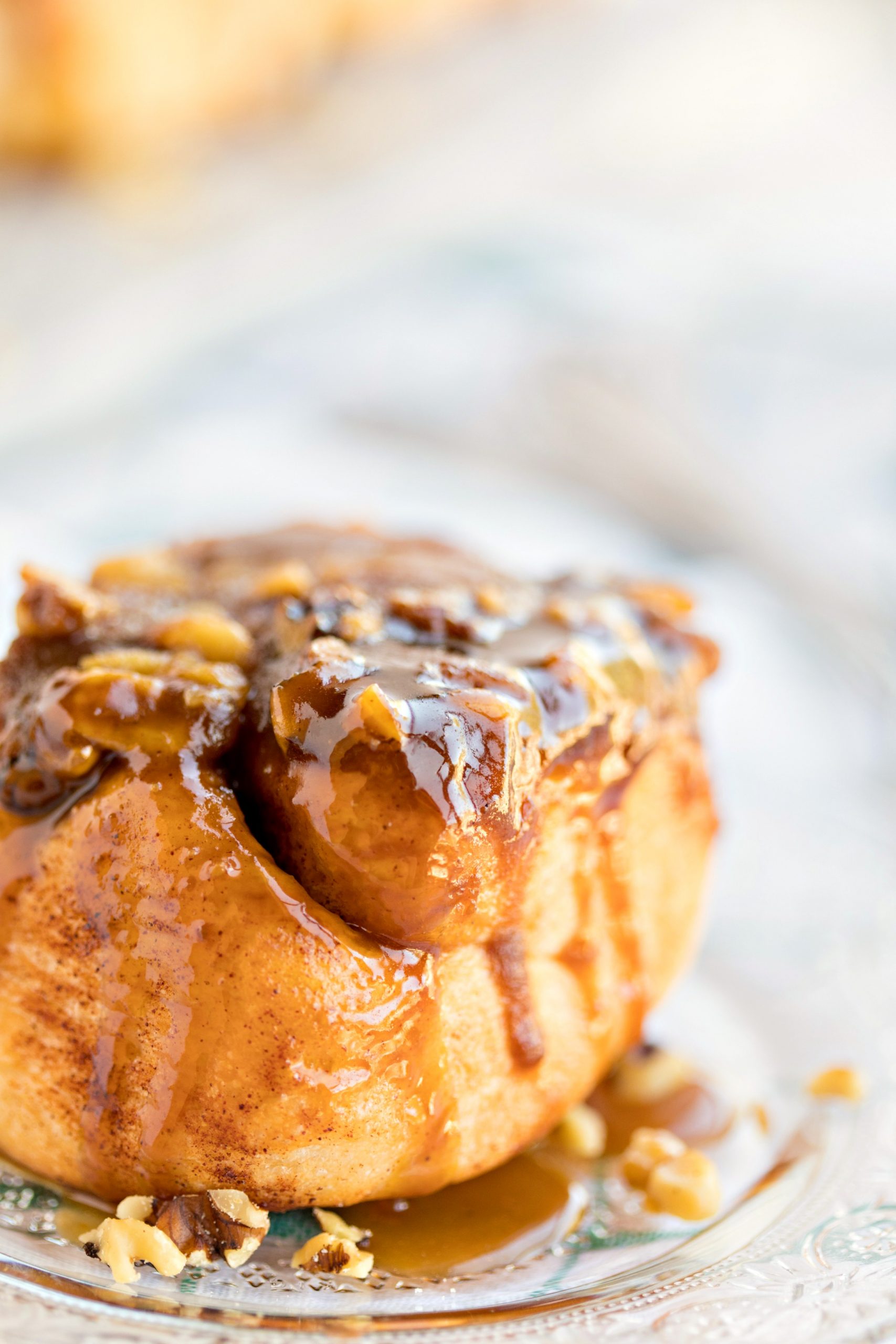 A delicious sticky bun dripping with caramel and topped with pecans