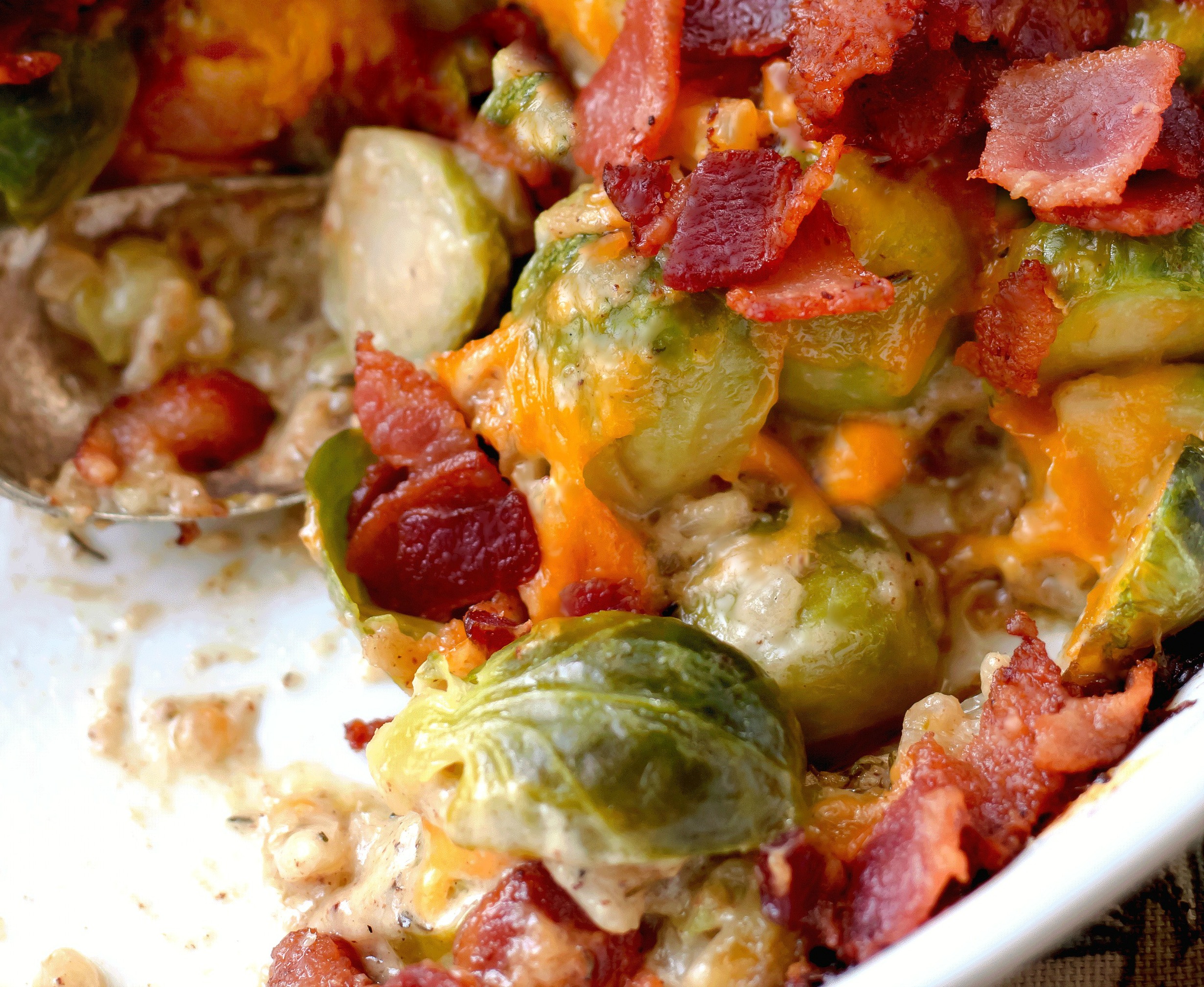 Brussels sprouts covered with cheese and bacon on a plate in a creamy sauce