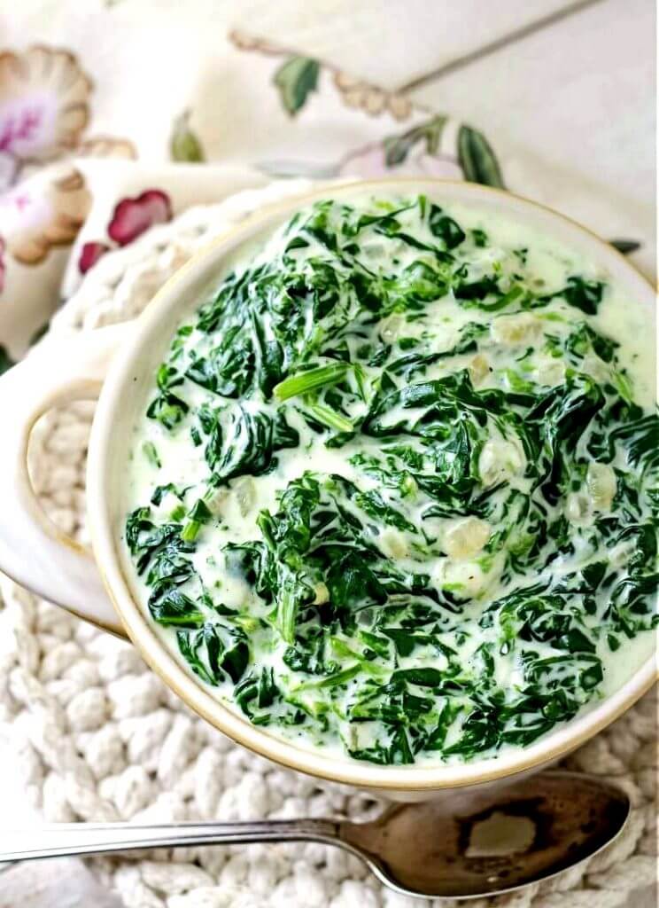 Fresh Creamed Spinach in a beige bowl sitting on a trivet