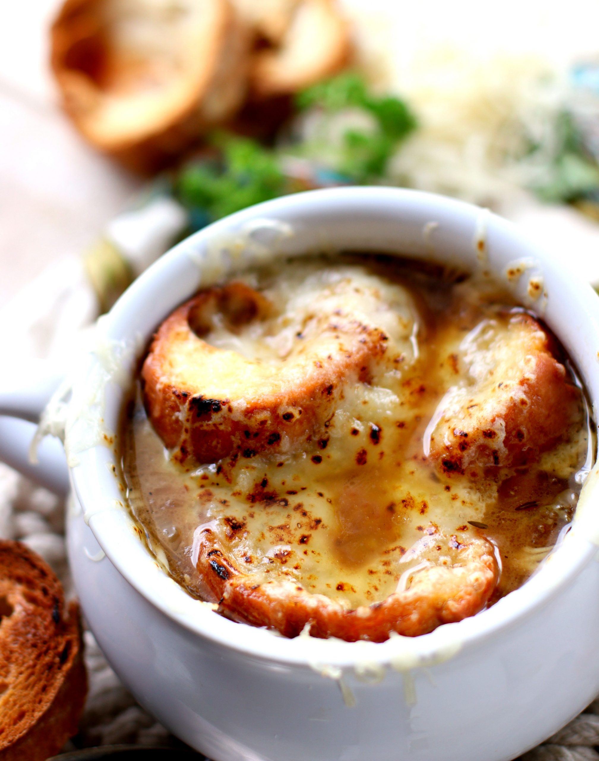A soup bowl with French Onion soup topped with cheese and croutons