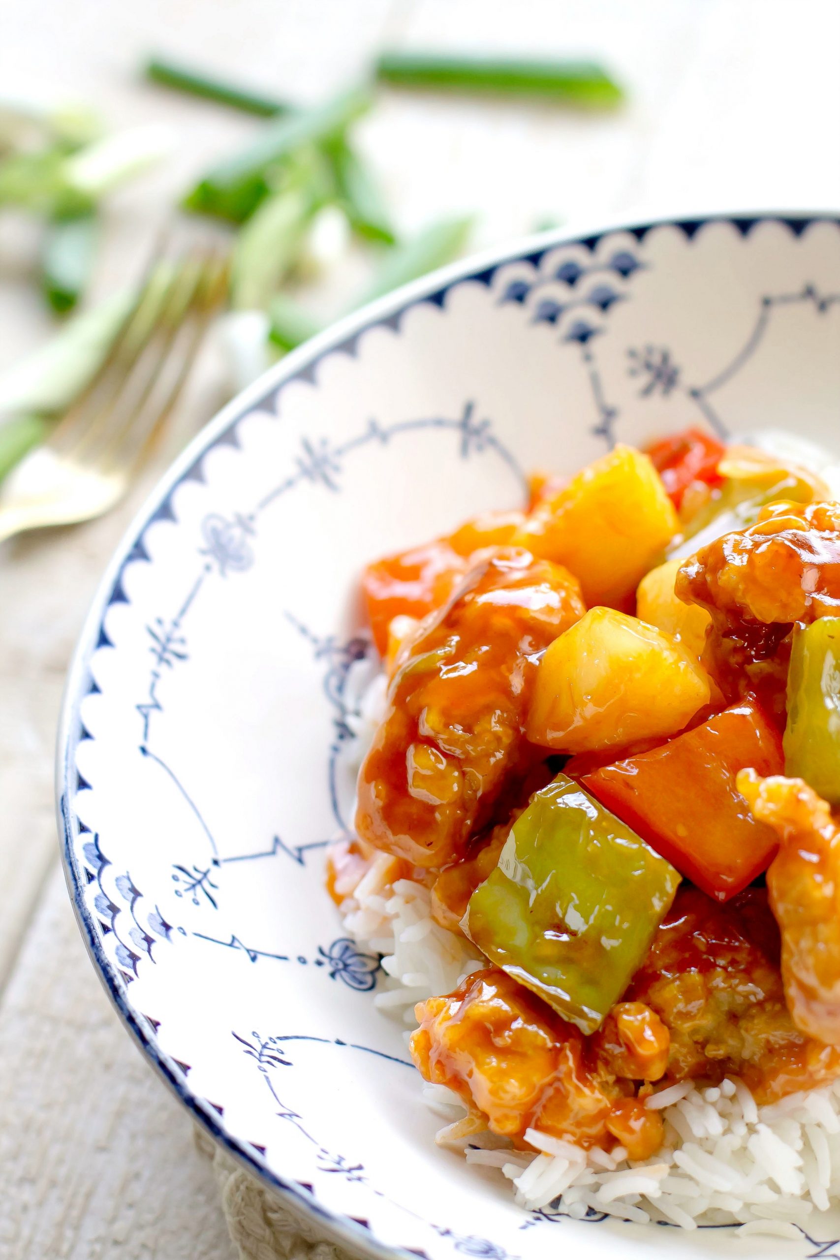 Sweet and sour pork with pineapples and peppers on a white and blue plate