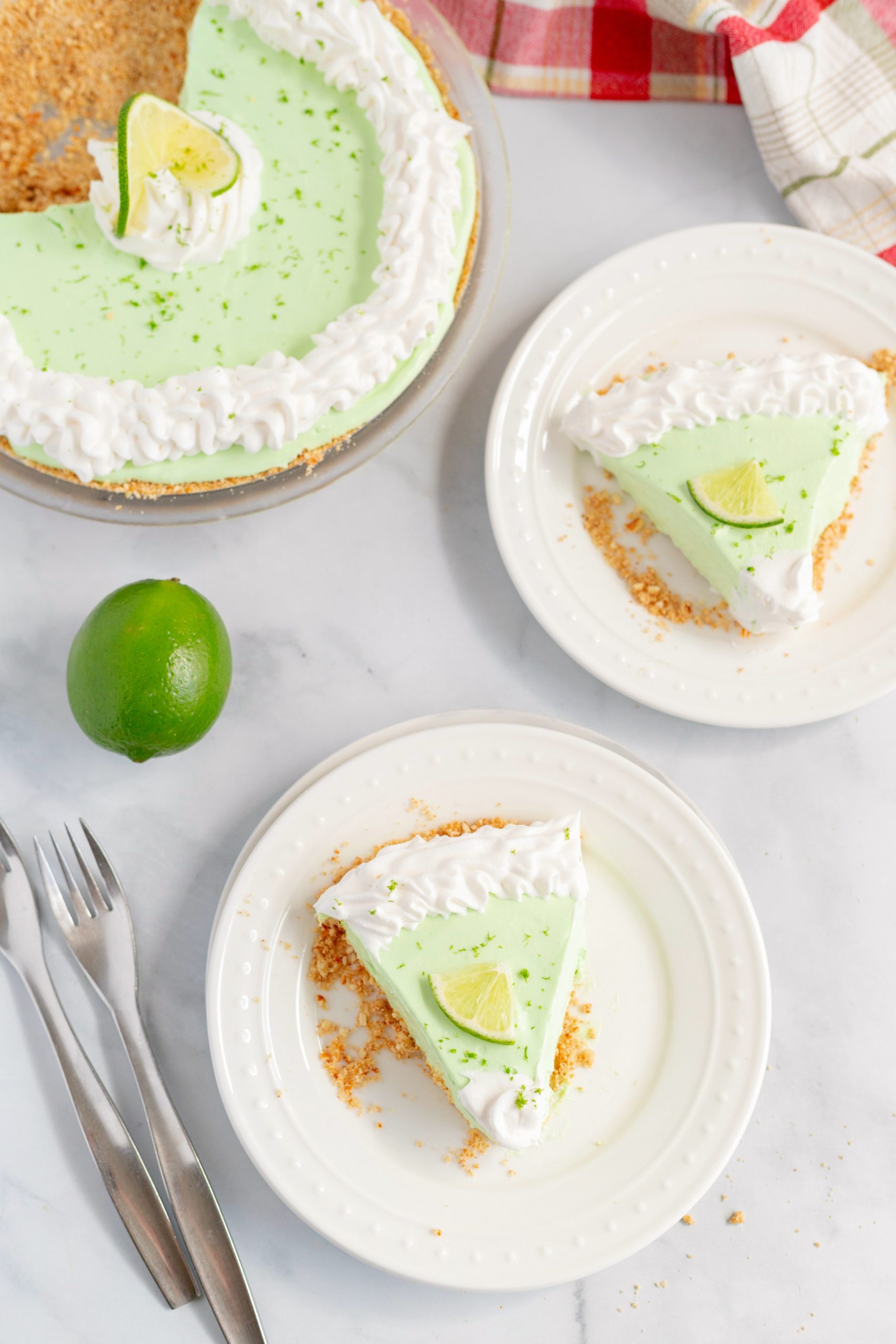 Slices of Key Lime Margarita Pie on white plates, fresh lime on the table